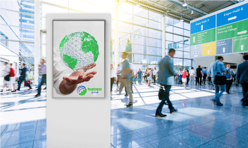 Sintra sign with a white background. It features a green globe being held in a hand. There is a circular logo of half a blue sphere and a green bar graph underneath. The text next to the logo says Business in green text, and Global in blue text. There is a busy trade show scene in the background with giant windows and signage.